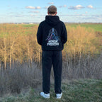Rückansicht eines schwarzen Honor Forgotten Hoodies am Model im Outdoor-Setting, großer grafischer Backprint sichtbar.
